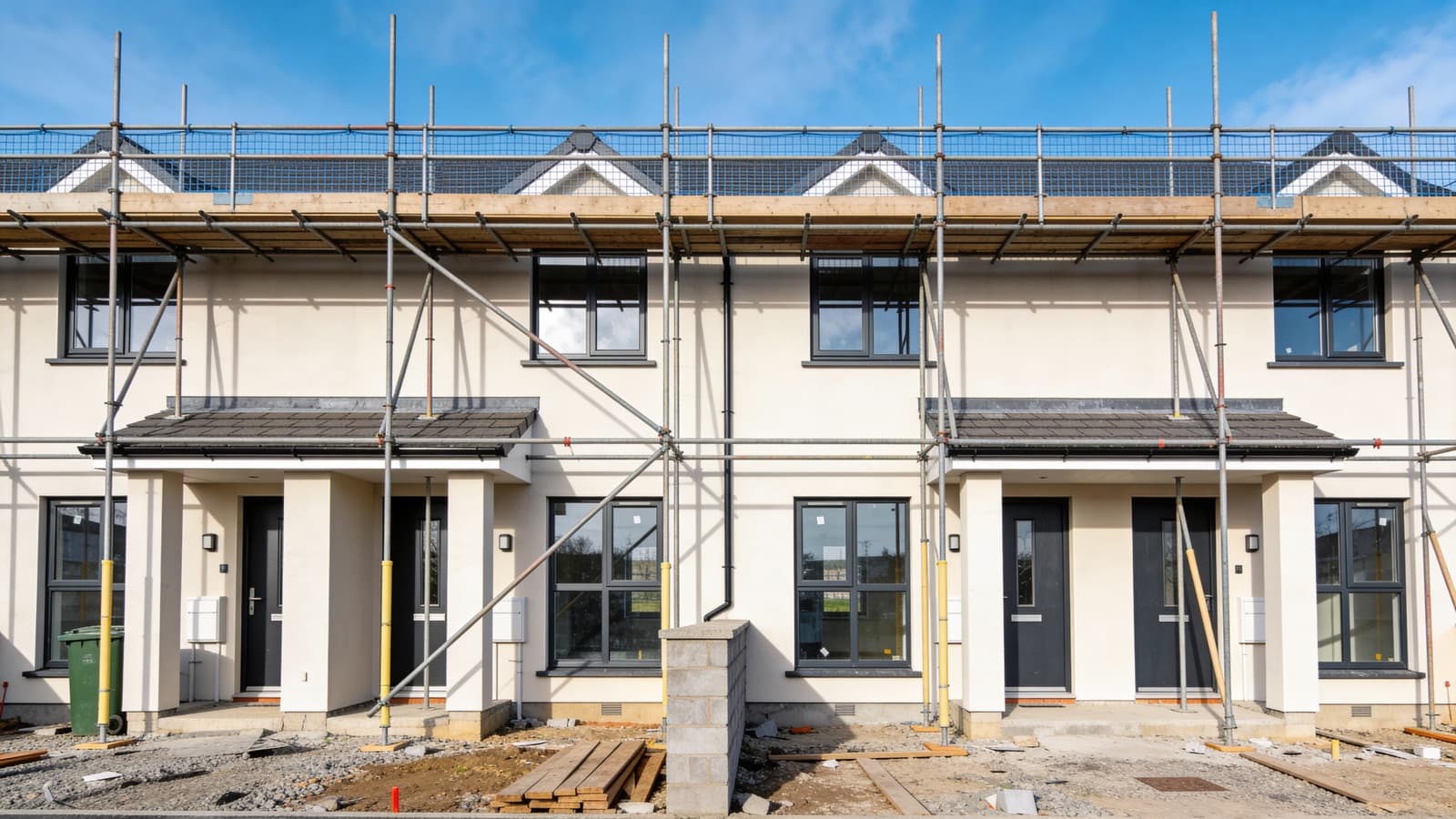 A row of modern new-build houses under construction in Ireland with scaffolding during the first-fix stage